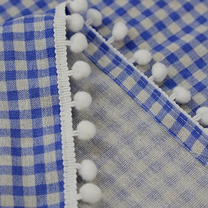 Blue gingham cafe curtain with white pom-pom trim detail in Nordic minimalist style