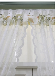 Détail du rideau en dentelle blanche avec motif végétal et bordure festonnée