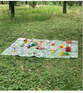 Detail einer feuchtigkeitsbeständigen Picknickmatte mit Blattmuster auf Gras