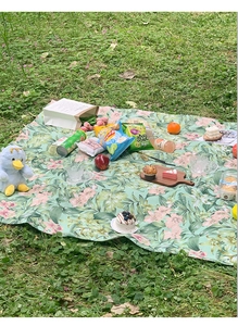 Detail der Picknickdecke mit Blumenmuster aus wasserdichtem Stoff auf grünem Gras im Freien