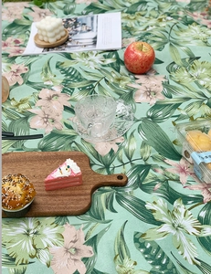 Detail der Outdoor-Picknickdecke mit tropischen Blättern und Blumen auf grünem Gras