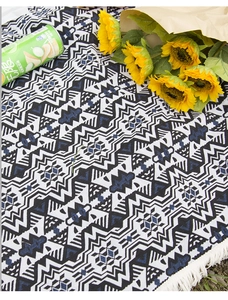 Close-up of Bohemian geometric knit picnic blanket with tassels on green grass