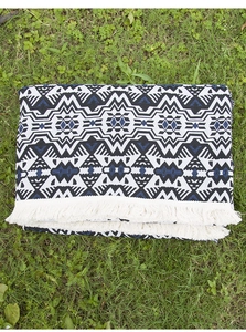 Close-up of bohemian woven picnic blanket with geometric patterns and white fringe edge