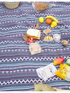 Detail of bohemian outdoor picnic mat with purple geometric wave texture on grass