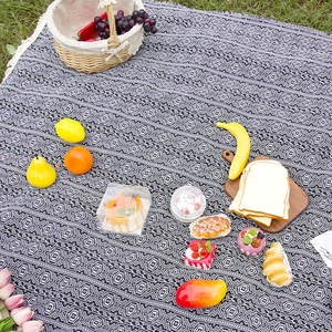 Bohemian black and white geometric picnic blanket with tassels on green grass