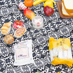 Bohemian geometric woven picnic mat in blue and white displayed with outdoor snacks