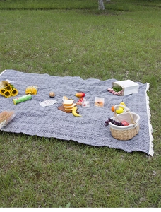 Detail of blue and white woven picnic mat with geometric patterns and cotton fringes