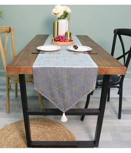 Detail of gray velvet table runner with gold geometric lines and white tassel trim