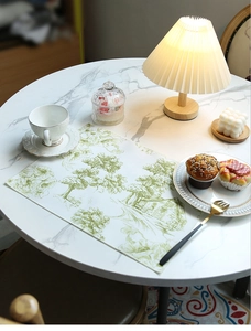 Close-up of waterproof linen placemat featuring a green pastoral landscape on a table