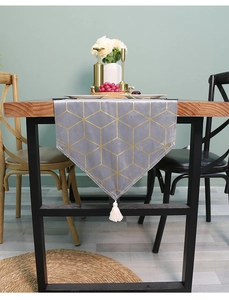 Close-up of grey velvet table runner featuring gold geometric patterns and a white tassel