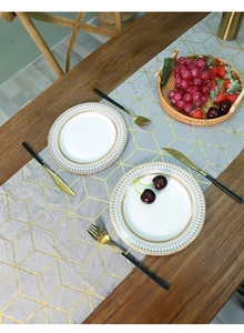 Close-up of gray velvet table runner with gold geometric cube patterns on wooden table