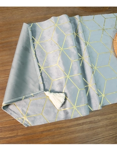 Detail of light blue velvet table runner with gold geometric patterns and white tassels