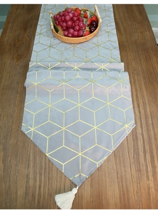 Detail of light gray velvet table runner with gold geometric lines and white tassels