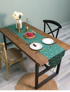 Close-up of dark green velvet table runner with gold geometric pattern and white tassel