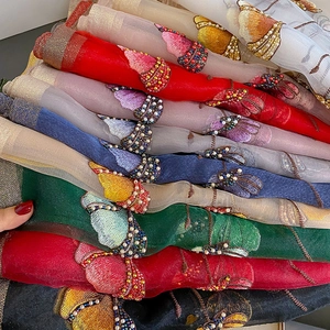 Detail of silk scarf featuring intricate butterfly embroidery and colorful hand-sewn beads