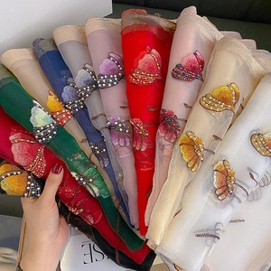 Detail of silk blend scarf featuring multi-color butterfly embroidery and pearl accents