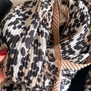Close-up of leopard print scarf featuring pleated texture and elegant brown tones