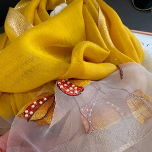 Detailed embroidery with beads and pearls on lightweight yellow silk shawl texture