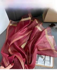 Dettaglio della sciarpa di seta bordeaux con strisce dorate e texture leggera