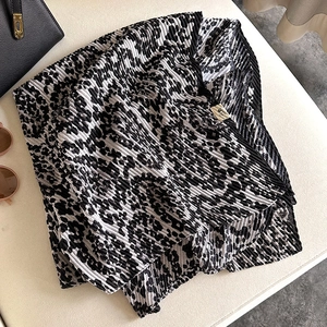 Detail of leopard print pleated scarf with black and white patterns on leather background
