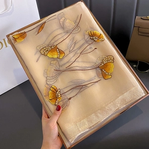 Close-up of silk blend scarf featuring yellow floral embroidery and pearl bead accents