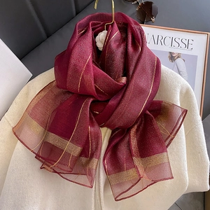 Dettaglio di sciarpa in seta bordeaux con fili d'oro su cappotto di lana bianco liscio