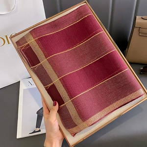 Dettaglio sciarpa bordeaux con strisce dorate in una confezione regalo di lusso
