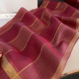 Dettaglio di sciarpa in seta bordeaux con strisce dorate metallizzate e trama fine