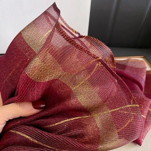 Vista macro di sciarpa in seta bordeaux con strisce dorate metallizzate e trama a rete