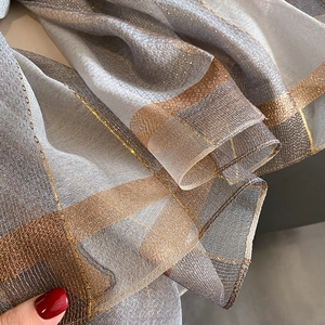 Dettaglio di sciarpa a righe in finta seta con fili metallici e trama tessuta fine