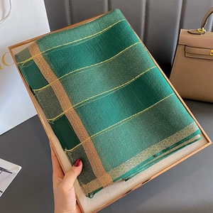Dettaglio di sciarpa in seta verde smeraldo con righe dorate in confezione regalo