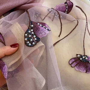 Macro detail of silk blend scarf with premium embroidery and pearl bead embellishments