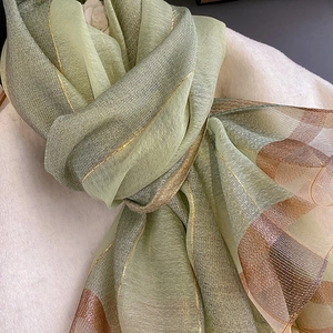 Dettaglio sciarpa effetto seta con trama a rete verde e bronzo e riflessi dorati