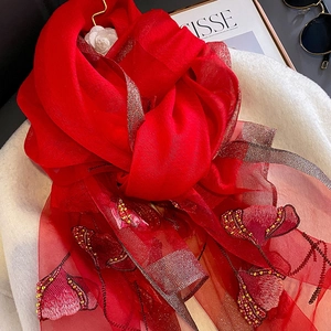 Detail of red silk blend shawl featuring floral embroidery and shimmering metallic lurex