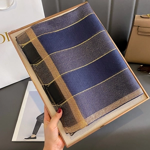 Dettaglio di sciarpa a righe blu navy e nera in finta seta con fili metallici dorati