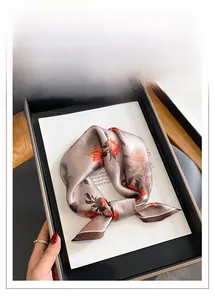 Dettaglio di un foulard in seta con motivi floreali arancioni in vassoio dorato
