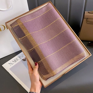 Dettaglio di sciarpa in finta seta a righe viola con trama di fili metallici dorati e maglia