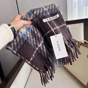 Detail eines dicken karierten Quastenschals in Braun und Blau mit Markenlabel