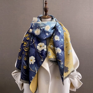 Dettaglio della sciarpa invernale con motivi floreali blu navy e frange morbide