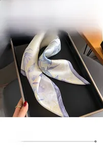 Gros plan d'un foulard en soie à fleurs lilas avec des coutures fines sur un plateau