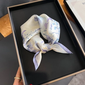 Vue détaillée du foulard en soie de mûrier à fleurs lilas noué en nœud sur présentoir noir