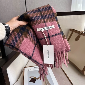 Nahaufnahme eines karierten Schals in Rosa und Braun mit weichen Fransen und Etikett