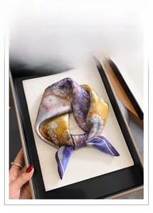 Vue détaillée d'un foulard en soie avec imprimé floral violet et orange sur un plateau