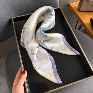 Élégant foulard en soie à fleurs présenté sur un plateau de présentation noir mat