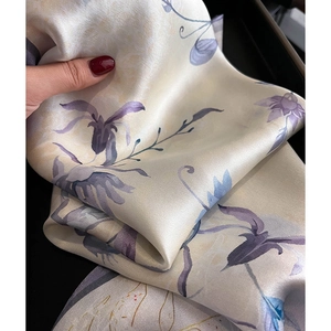 Gros plan d'un foulard en soie avec motifs de lys mauves et texture satinée