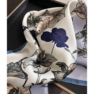 Détail d'un foulard en soie aux motifs de roses bleues et de lys sur tissu crème
