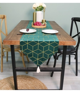 Close-up of dark green velvet table runner with gold geometric pattern and white tassel