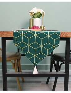 Detail of dark green velvet table runner with gold geometric pattern and white tassel