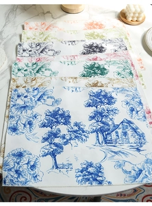 Detail of multi-color cotton linen placemats showing rural landscape print and overlock stitching