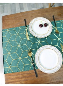 Detail of dark green velvet table runner with gold geometric patterns and dinnerware